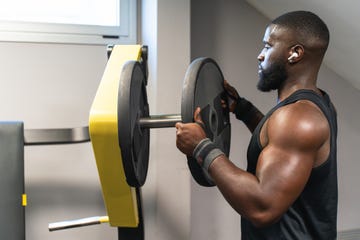 black bodybuilder putting more weight on the gym machine