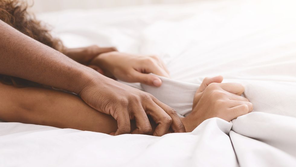 black couple hands pulling white sheets in ecstasy