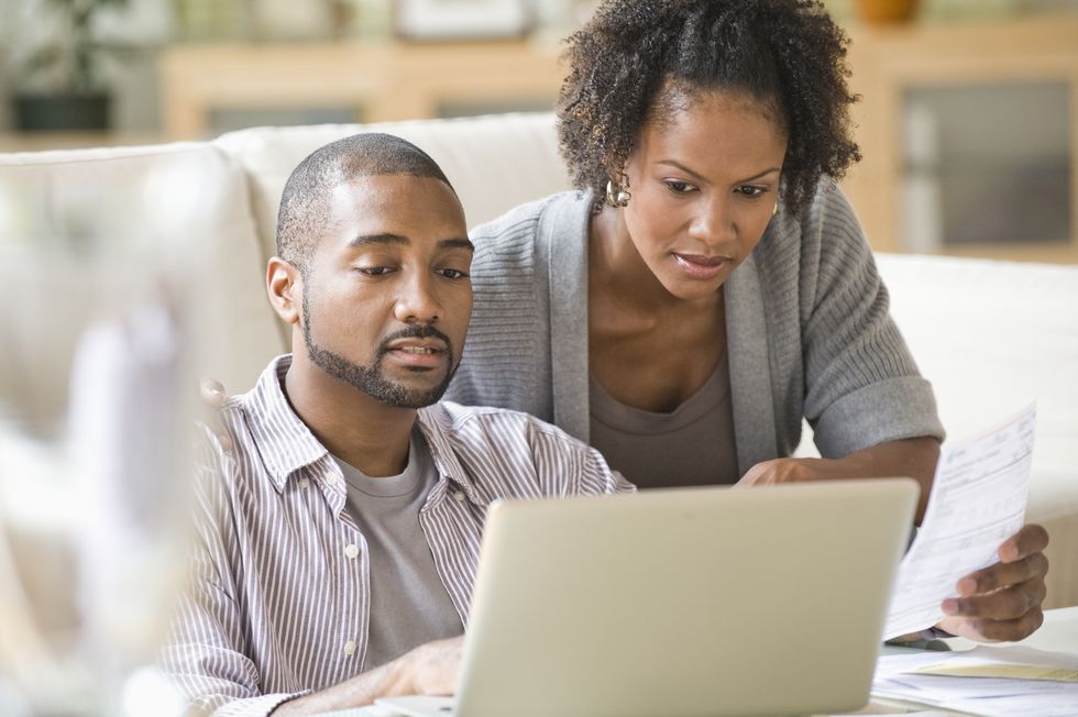 black couple paying bills using laptop