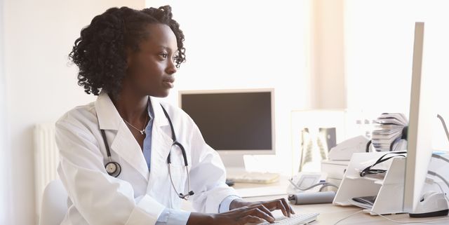 Black doctor typing on computer