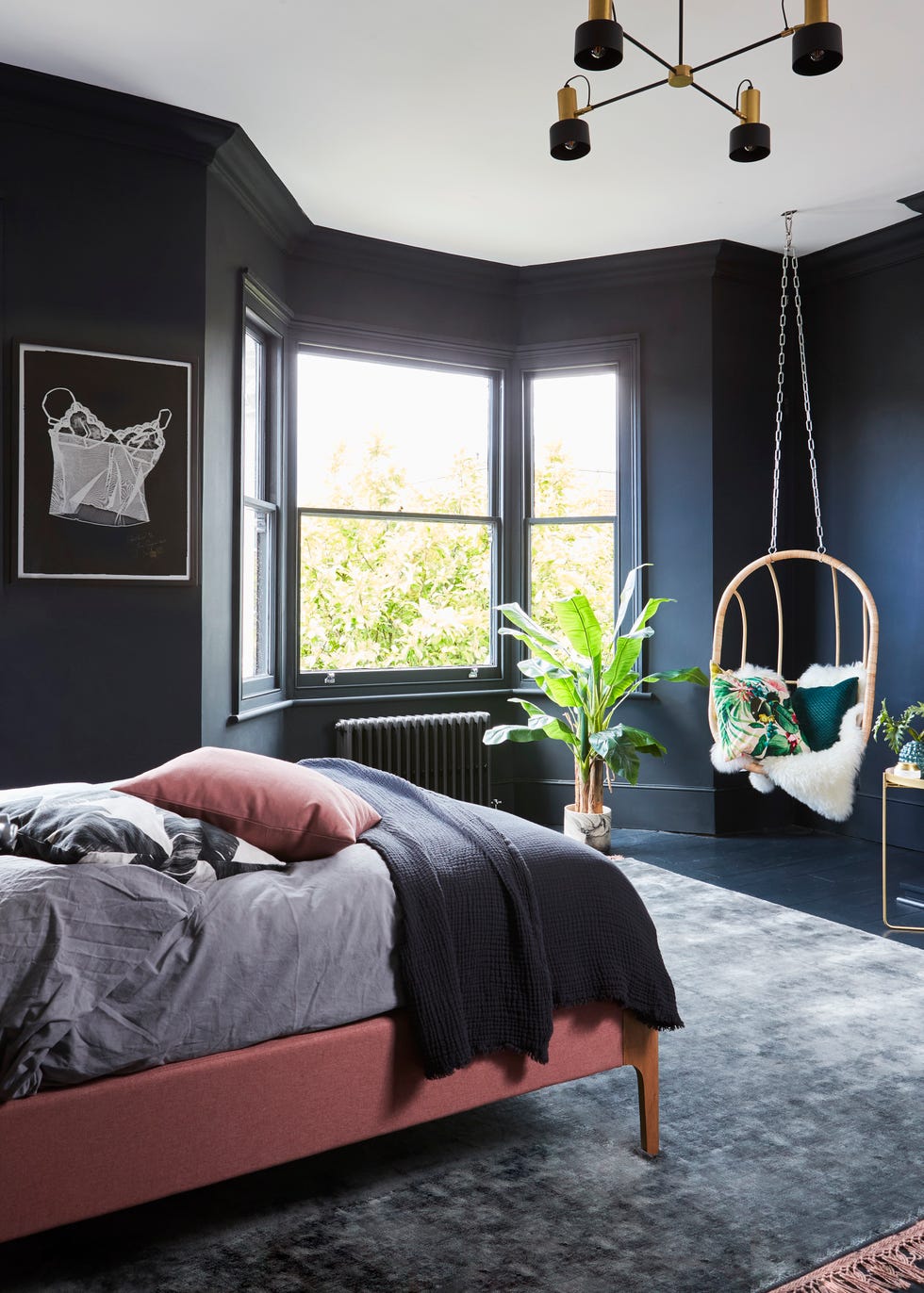 a black bedroom with a hanging egg chair and pink bed