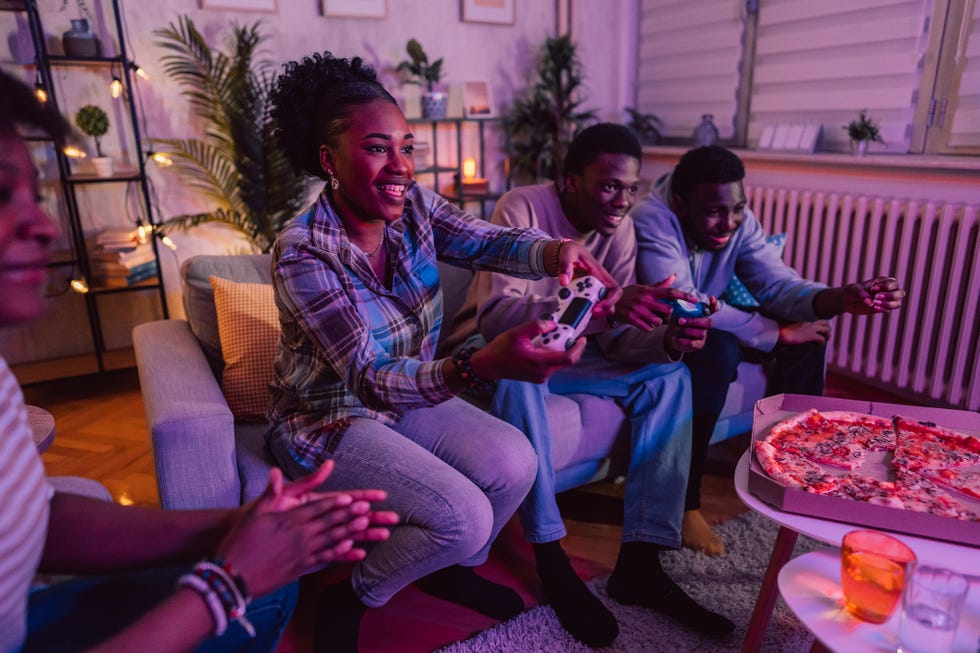 black family playing video games and eating pizza together in the living room