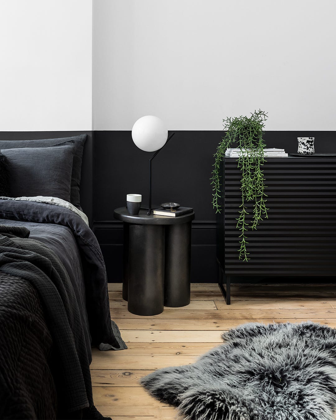 modern bedroom with dark tones featuring a bedside table and a plant