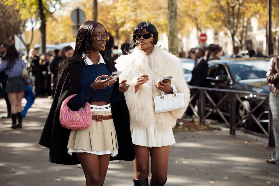 paris, france october 01 l r a guest wears beige pleated mini skirt, navy blue sweater, black jacket and pink bag and a guest wears white pleated min skirt, white fur coat and white bag outside the miu miu show during womenswear springsummer 2025 as part of paris fashion week on october 01, 2024 in paris, france photo by raimonda kulikauskienegetty images