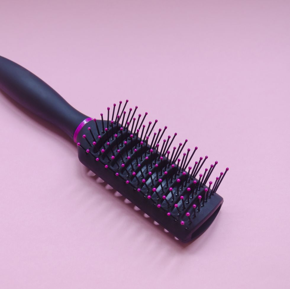 escova de cabelo preta em fundo rosa