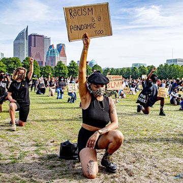 vrouw met mondmasker en protestbord tijdens de demonstraties tegen racisme op het malieveld in den haag
