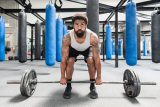 black man lifting barbell in gymnasium