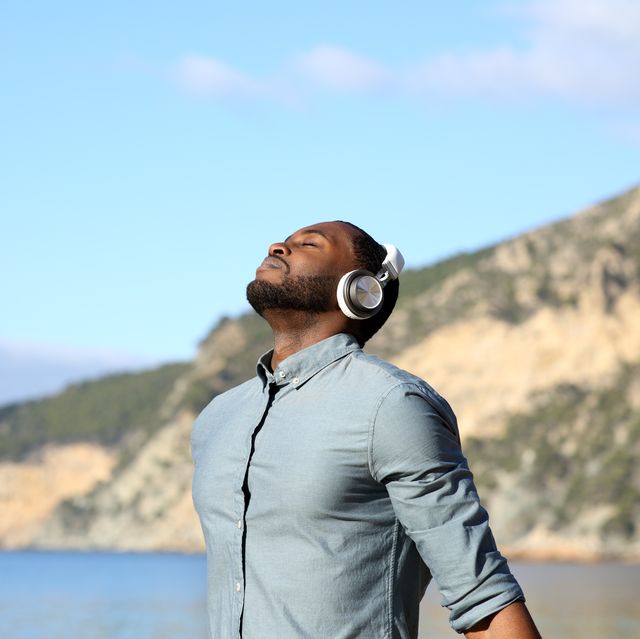 black man meditating with headphones on the beach