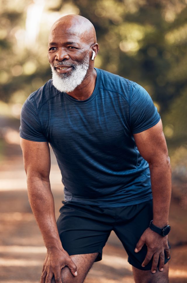 black man, running break and breathing for fitness, exercise and workout in nature, park or garden senior male, sports rest and smile for motivation, health and outdoor wellness training with music