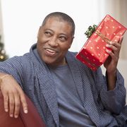 black man shaking gift in living room at christmastime