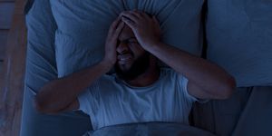 black man suffering from headache or migraine at night
