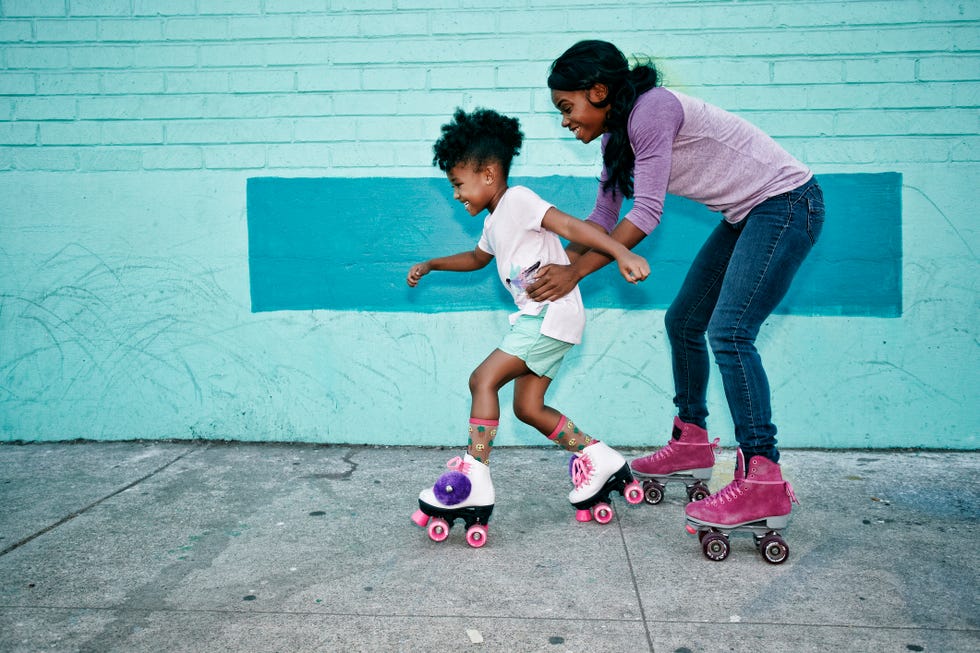 a mother and daughter roller blading on the side walk