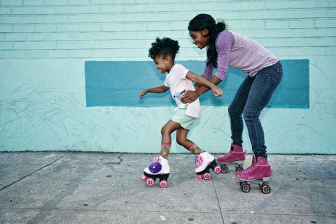 a mother and daughter roller blading on the side walk