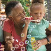black multi generation family blowing bubbles outdoors