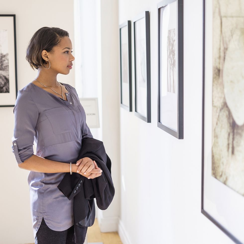 staycation ideas - Black woman admiring paintings in art gallery