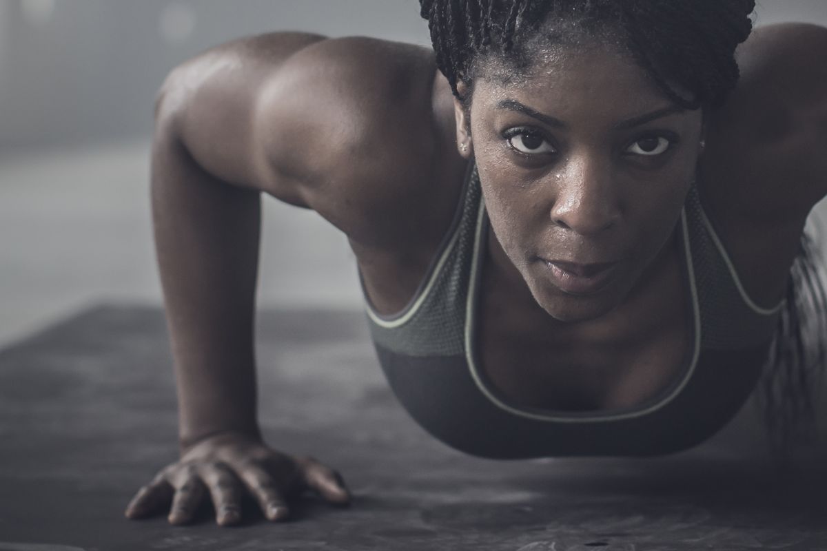 black woman doing pushups in dark gym