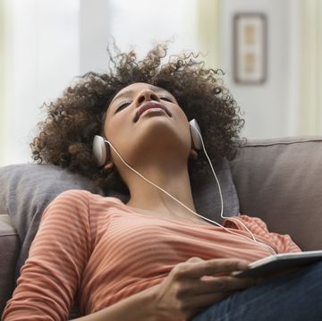 Black woman listening to headphones on sofa