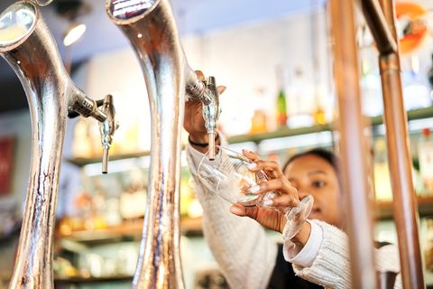 black woman pouring a glass of tap beer