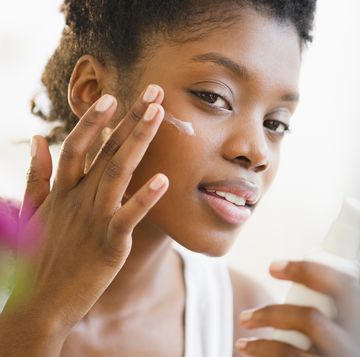 black woman putting on face lotion