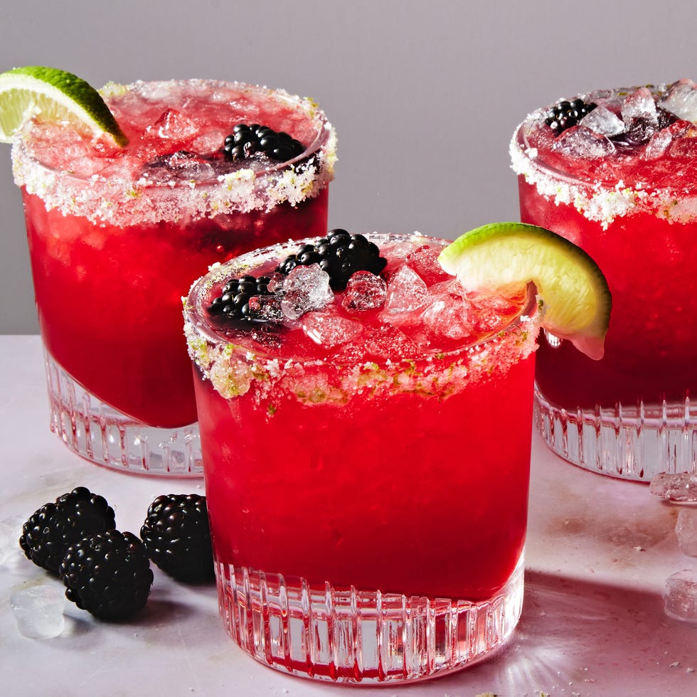 blended pink blackberry margarita with a rugar rim, lime wedge and blackberries