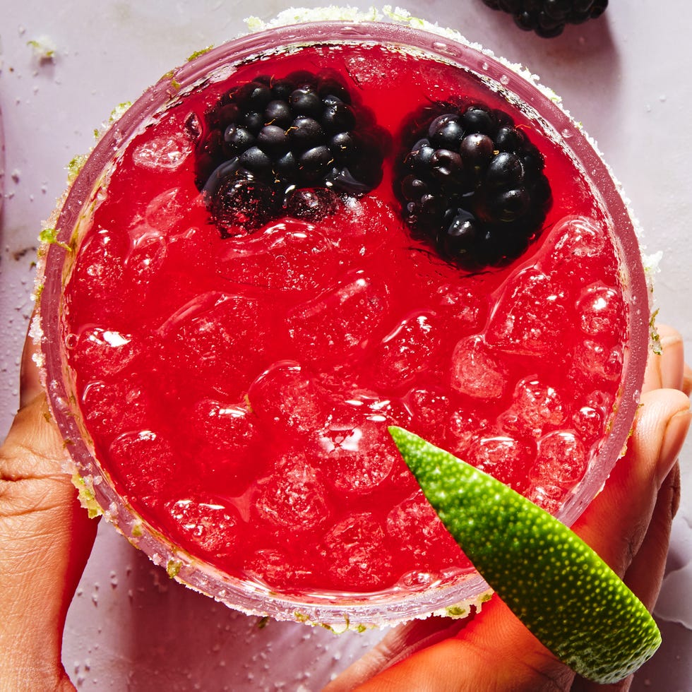 blended pink blackberry margarita with a rugar rim, lime wedge and blackberries