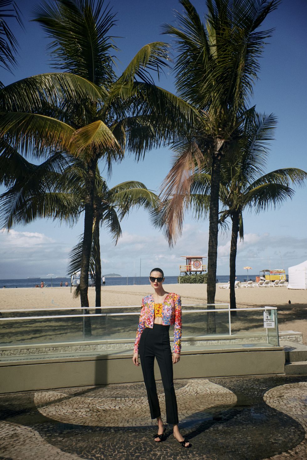 a person standing next to a palm tree on a beach