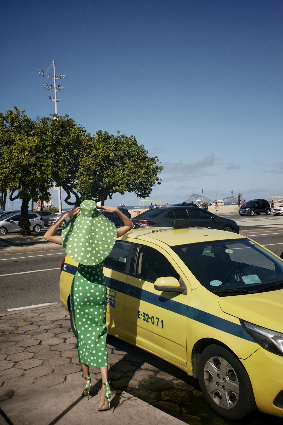 a person in a garment standing next to a yellow car