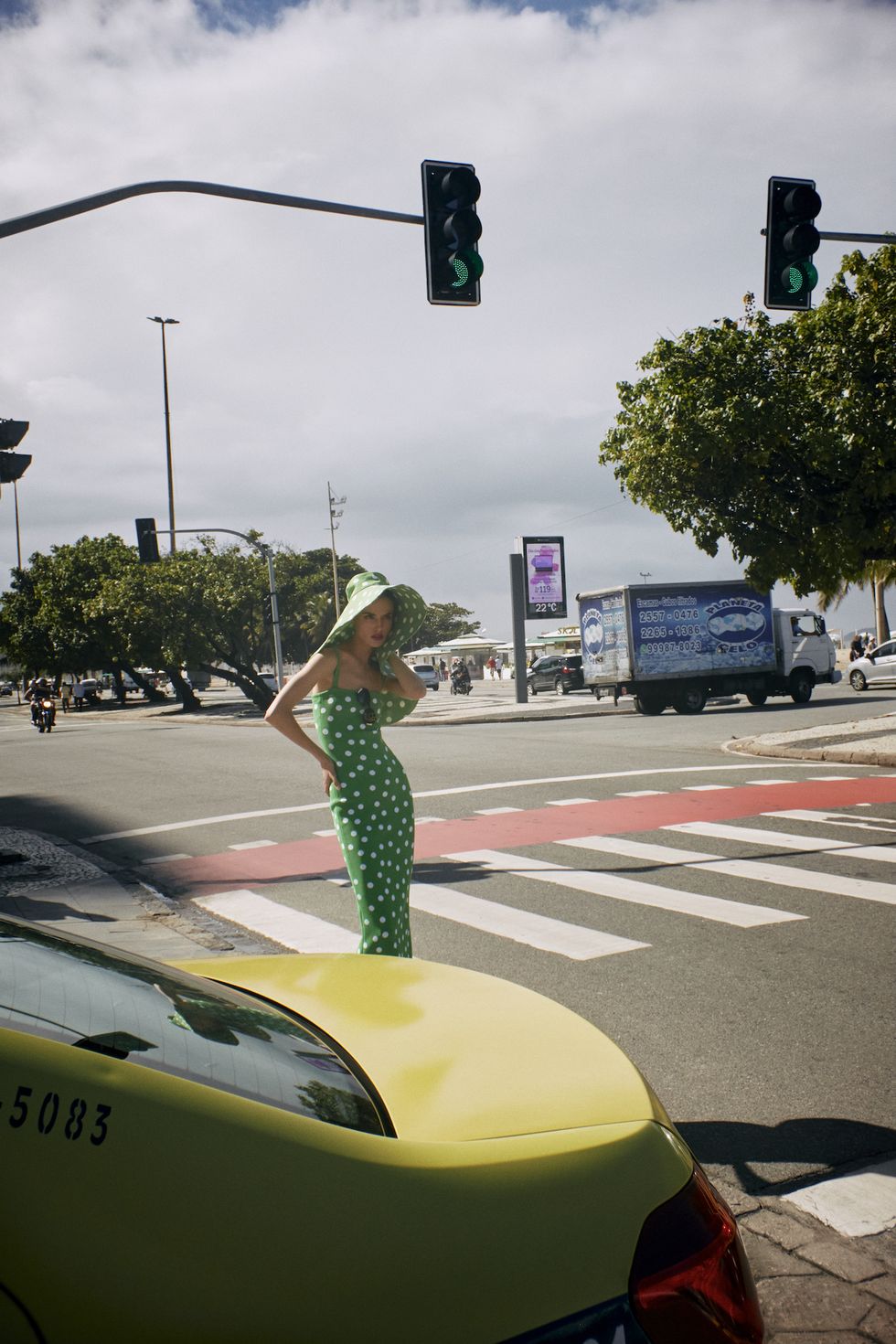 a person in a green dress stands at a crosswalk