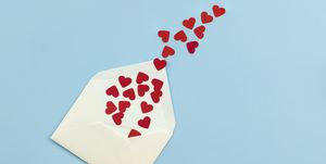 blank envelope full of red hearts shapes paper against blue background