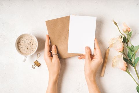 blank white card with craft paper envelope in hands