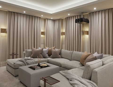home theater with drapes on the walls, large grey couch with pillows and blankets