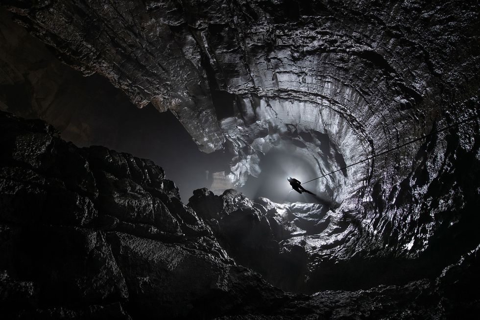 De grot van Um Ladaw omvat drie verticale kamers waaronder deze perfect ronde schacht Hier klimt de Britse grotonderzoeker Nicky Bayley aan een touw naar boven In het moessonseizoen vult de grot zich met water en wordt hij onbereikbaar