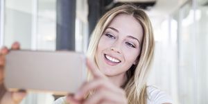 Blond woman at the dentist's taking selfie of bleached teeth
