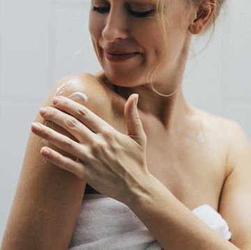 blonde caucasian woman applying body lotion