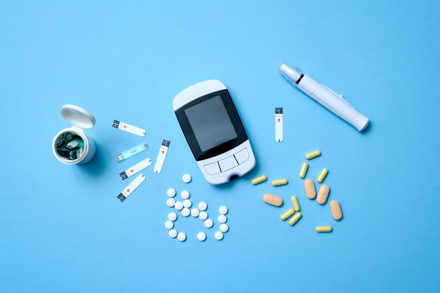 blood glucose test, pills, and a needle lie on a blue background