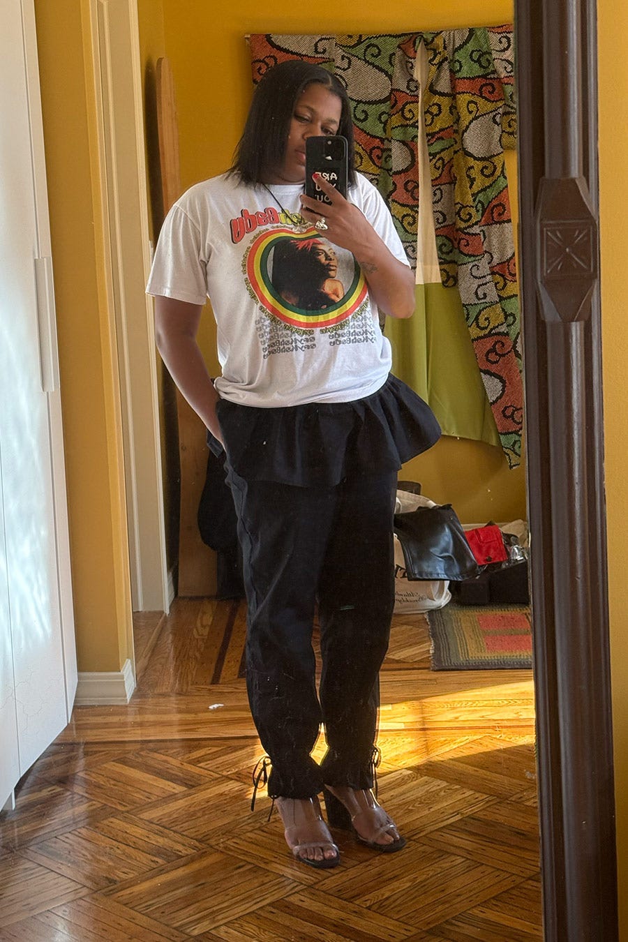 mirror reflection of a person wearing a graphic tshirt and stylish pants showcasing a casual outfit