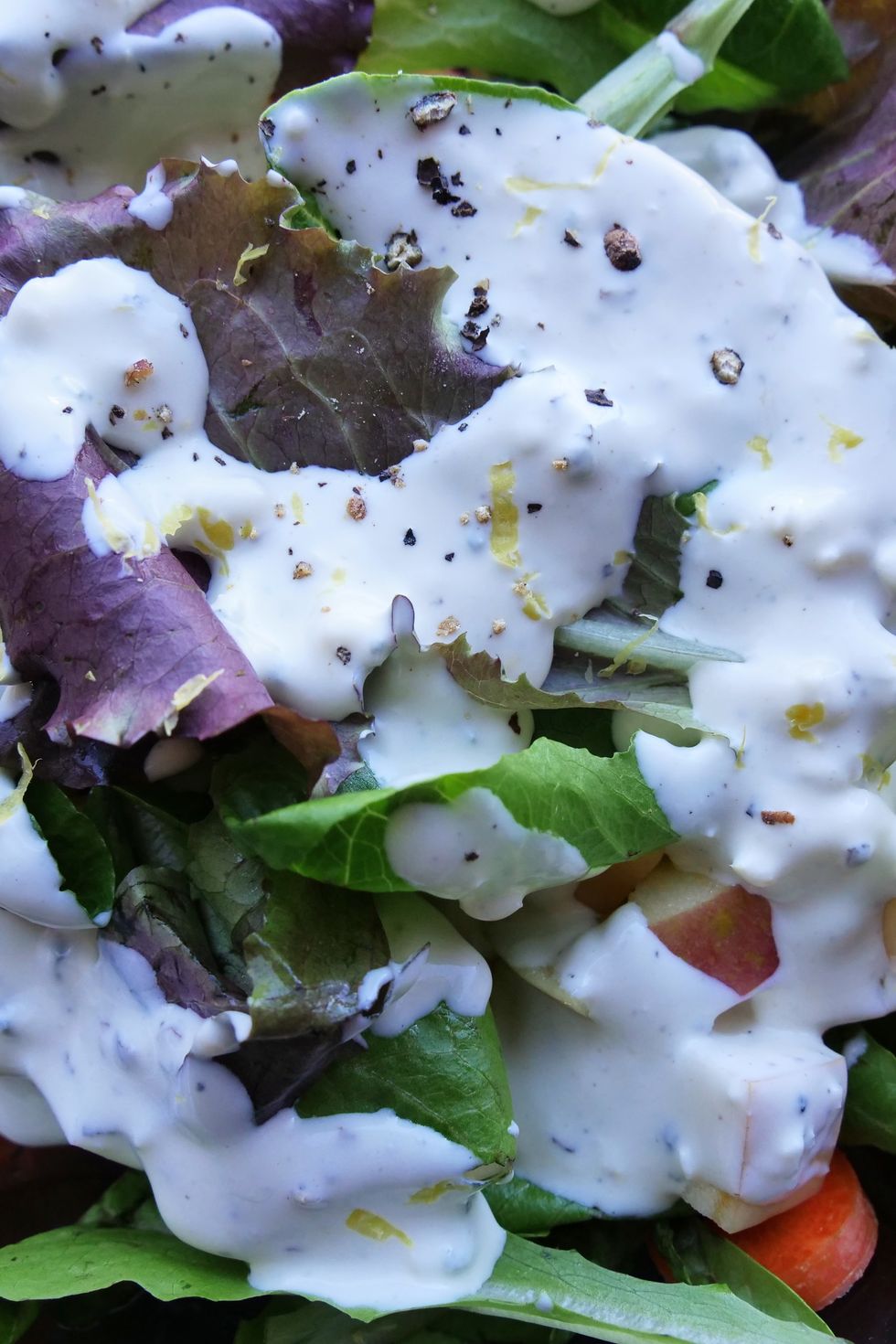 blue cheese dressing drizzled on top of a simple green salad