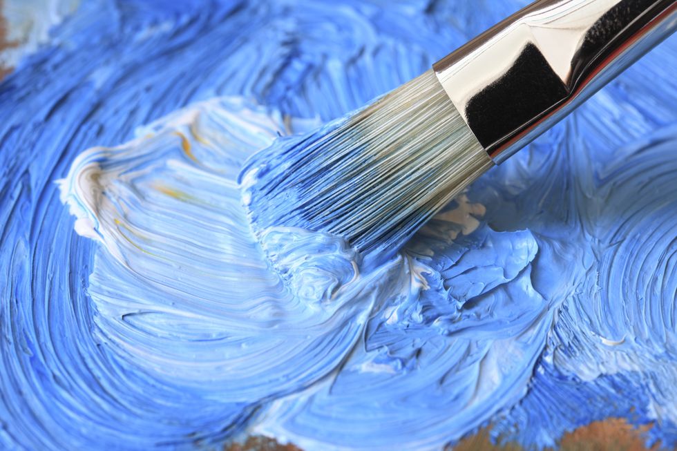 Paintbrush with blue oil paint on a classical palette