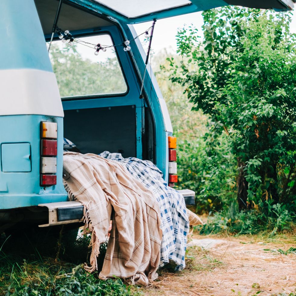 bluewhite retro van in nature, with cozy decorations, blanket and pillow, vacations in nature concept