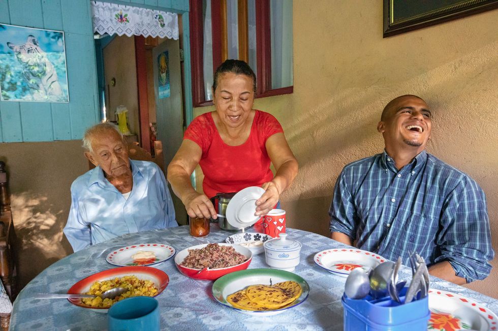 Paulina Villegas zet haar vader Pachito 102 en haar neef Sixto een stevig ontbijt voor dat vaak wordt gegeten in de streek Nicoya op Costa Rica Het ontbijt bestaat uit koffie eieren rijst en bonen en tortillas die zijn bereid op een fogn een houtgestookt fornuis