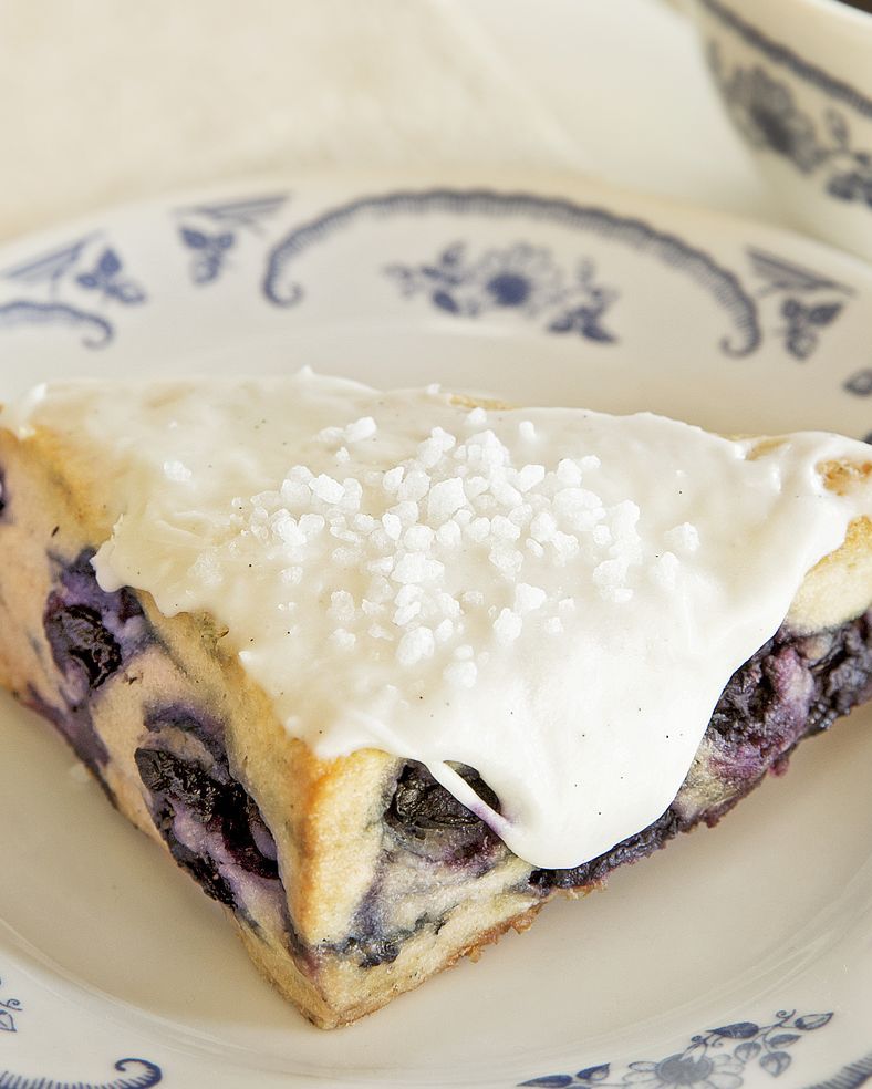 blueberry scones with vanilla icing on white and blue plate