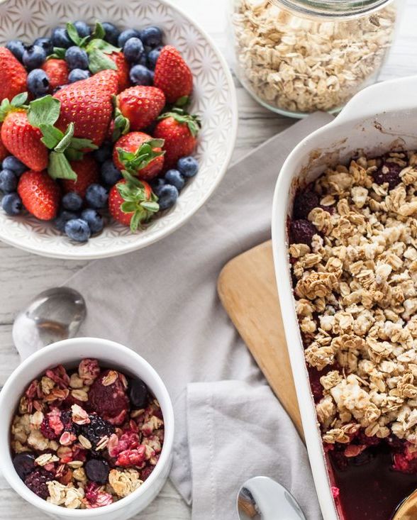 easy granola berry crisp in two mugs with bowl of mixed berries