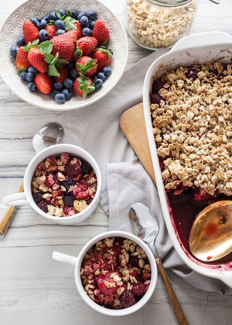 easy granola berry crisp in two mugs with bowl of mixed berries