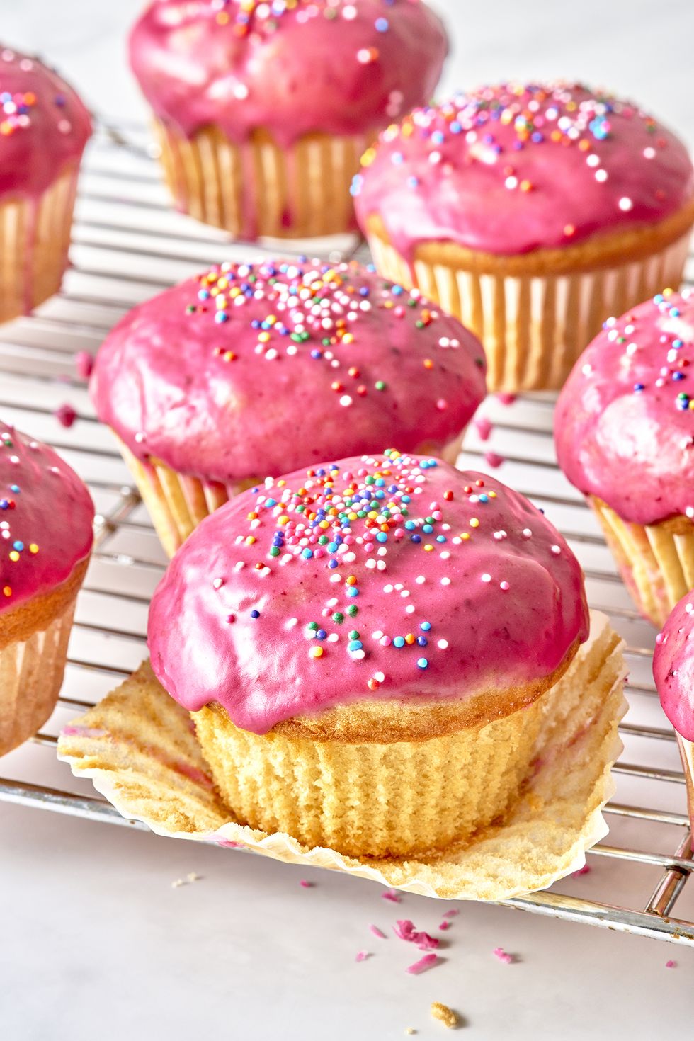 muffins topped with pink blueberry glaze and sprinkles