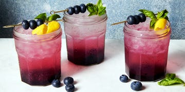 gin spritz in a jam jar garnished with a lemon twist and blueberries