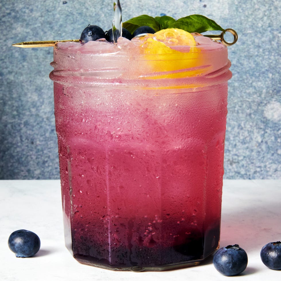 gin spritz in a jam jar garnished with a lemon twist and blueberries