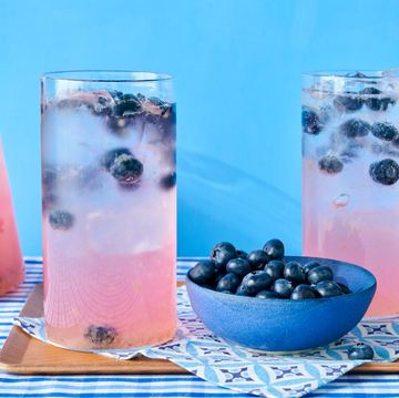 a group of glasses with liquid in them and a bowl of berries