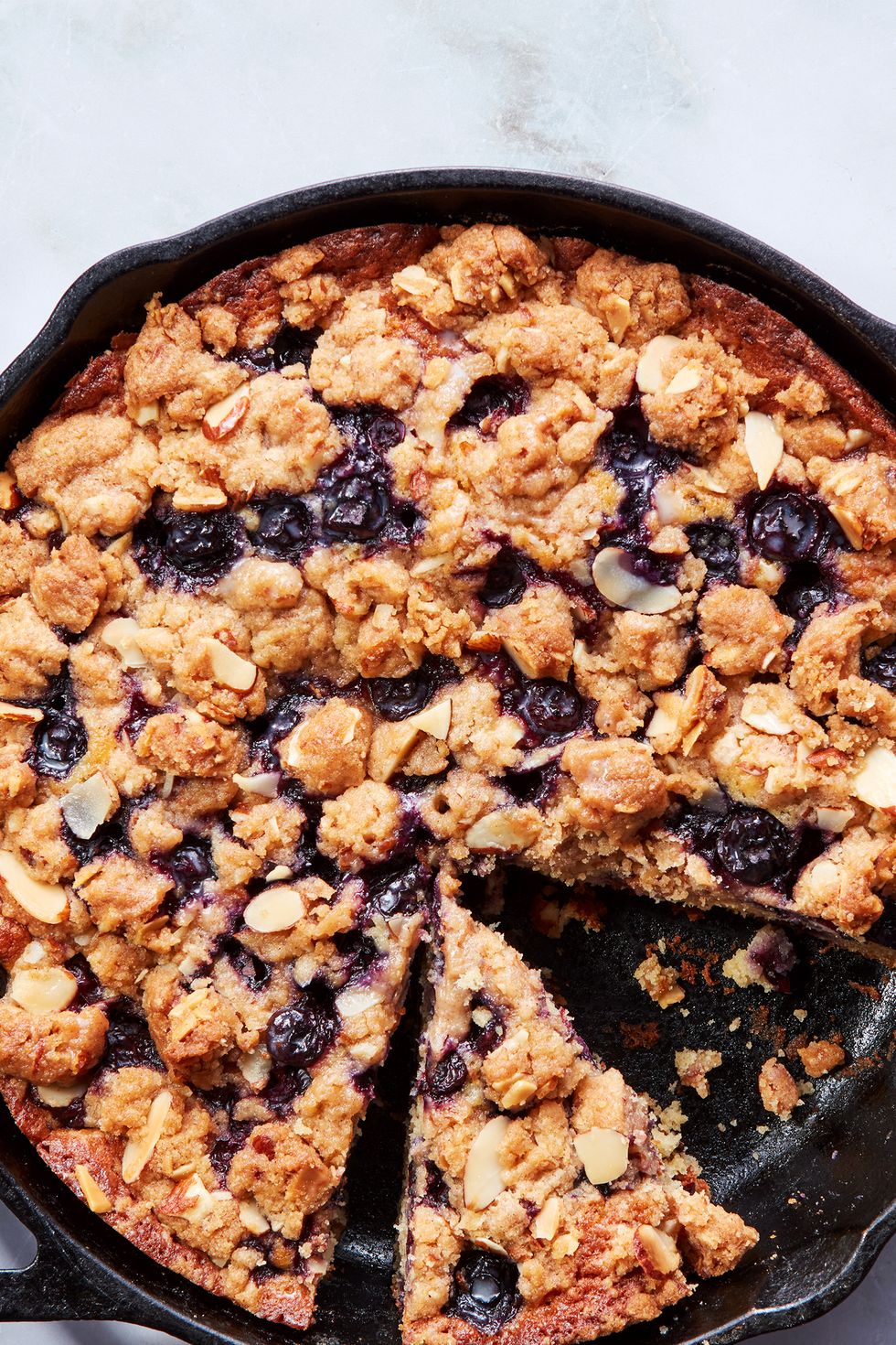 blueberry cake in a skillet topped with a crumble