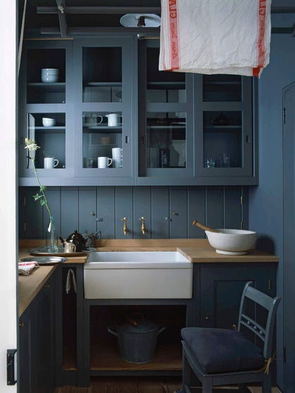 The kitchen, including the cabinets, paneled backsplash, walls, doors and ceiling, is finished in a blue-gray paint.