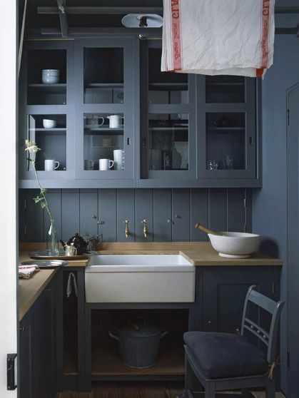 kitchen ensconced in blue gray paint including the cabinets, paneled backsplash, walls, door, and ceiling